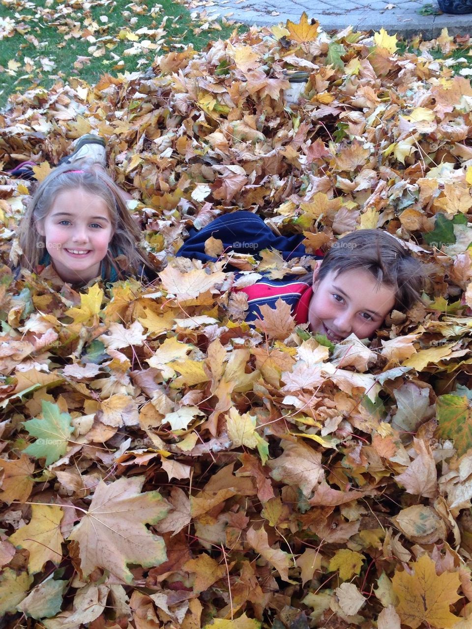 Boy and girl lying on autumn leafs