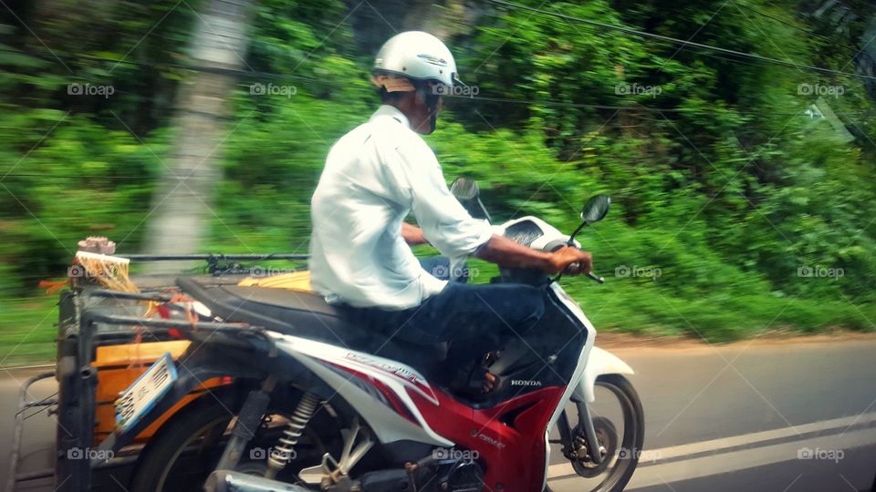 Krabi local driving on a scooter. Photo in motion.
