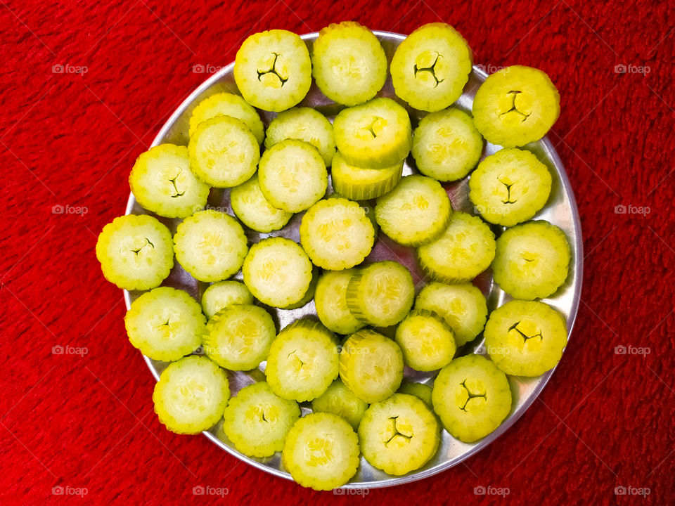 Fresh cucumber slices in steel plate on red background