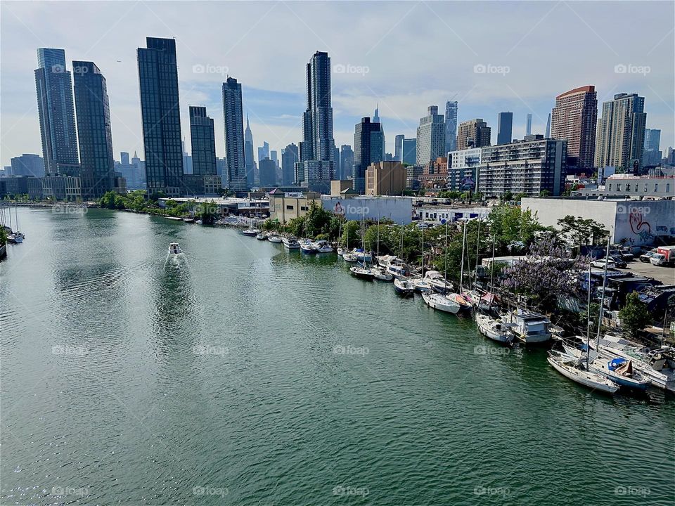This is beautiful “Newtown Creek” with its many boats seen from the “Pulaski Bridge” that connects LIC to “Greenpoint”, Bklyn. Across the “East River” we see “Manhattan” including the “Empire State Building”. 2024. Hypnotic Productions