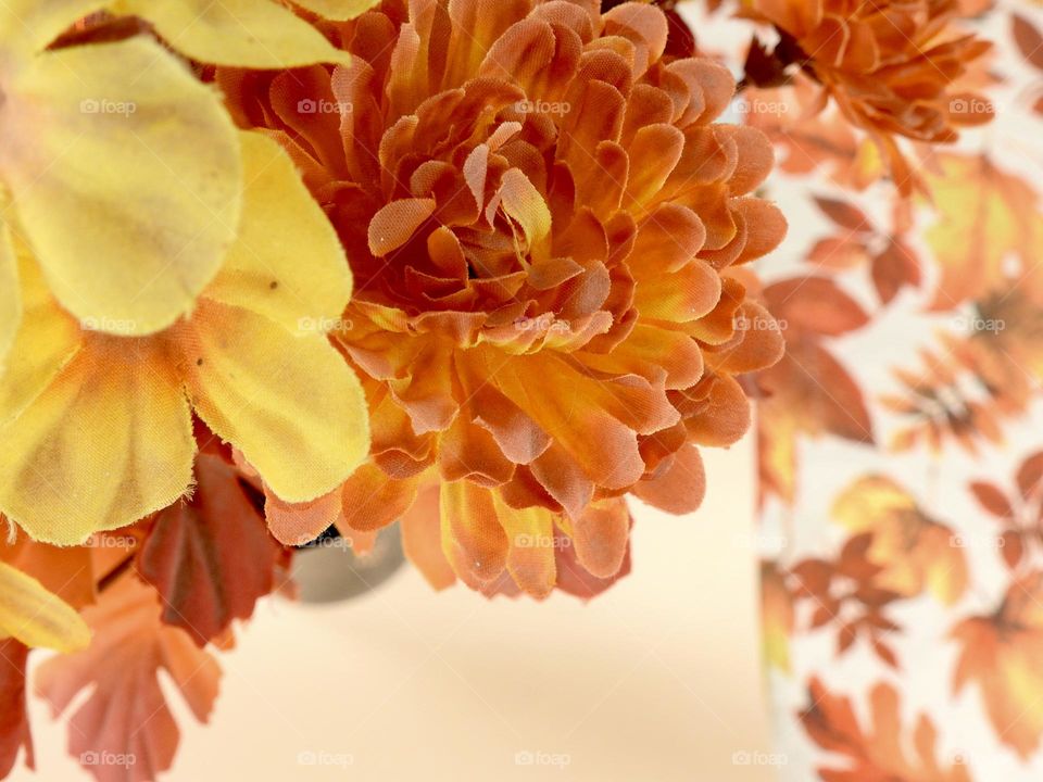 Bouquet for decoration in the autumn fall orange leaves color and yellow close-up macro seen from above in a vase on top of a leaf background on the ground.