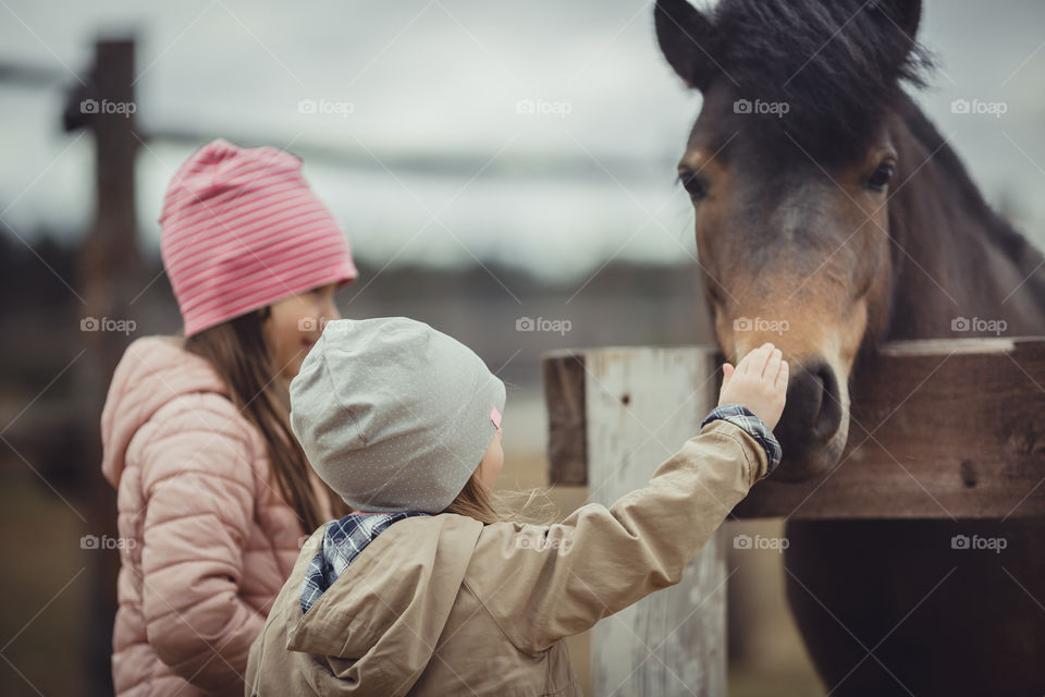 Little sisters with pony, outdoor portrait 