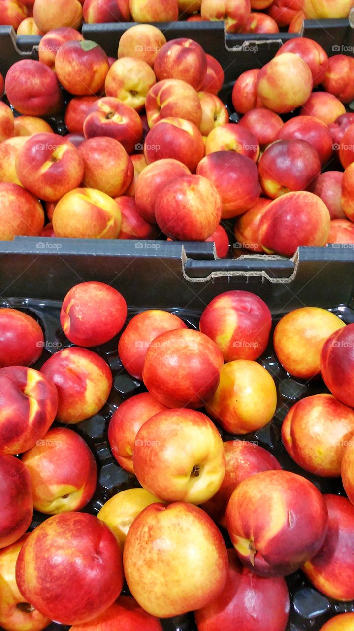 Nectarines placed in cardboard boxes for sale in a supermarket. Nectarines are botanically related to peaches. These are sold as fresh produce.