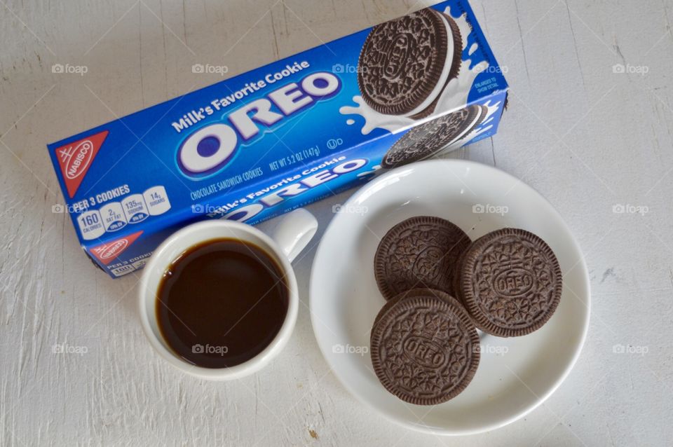 Flat lay of A pack of Oreo cookies with a plate of cookies and a cup of coffee on a white