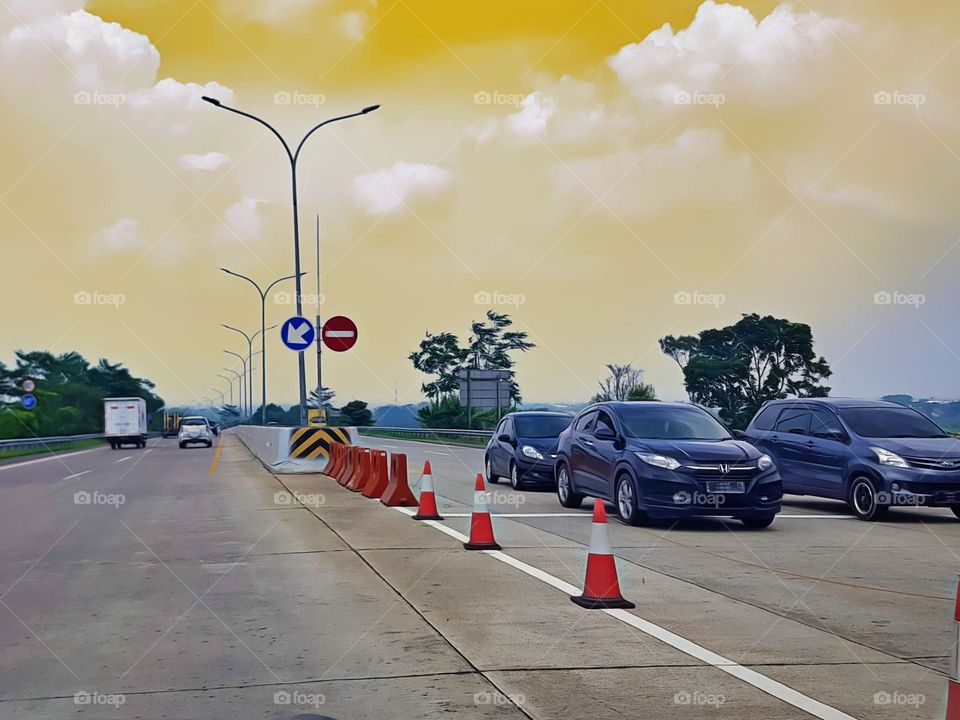 Traffc conies, traffic block, traffic sign, two lane toll road dividers, as road medians, made of plastic or rubber, alternating red and white, black base, installed parallel to a distance of 1 to 2 meters, view before the toll gate, highway barriers