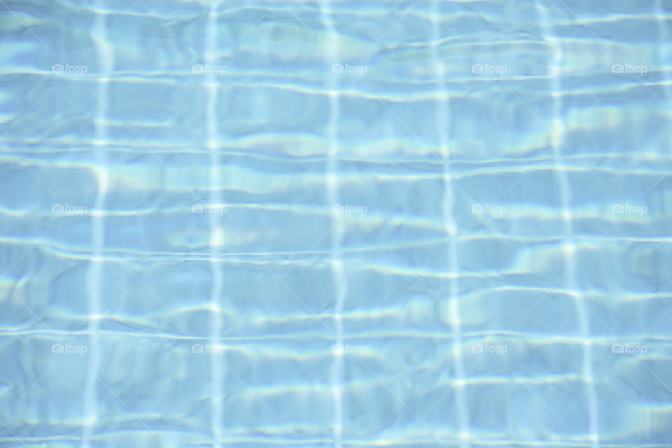 The blue water waves by wind and sunlight reflecting surface In the swimming pool.