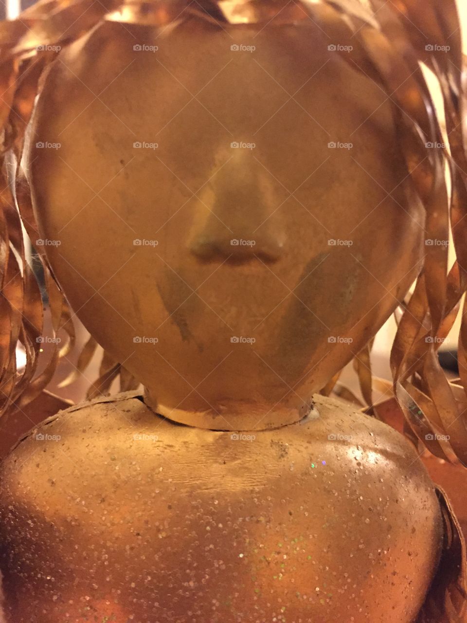 Very  close close-up of a gold colored tin angel head decoration.   