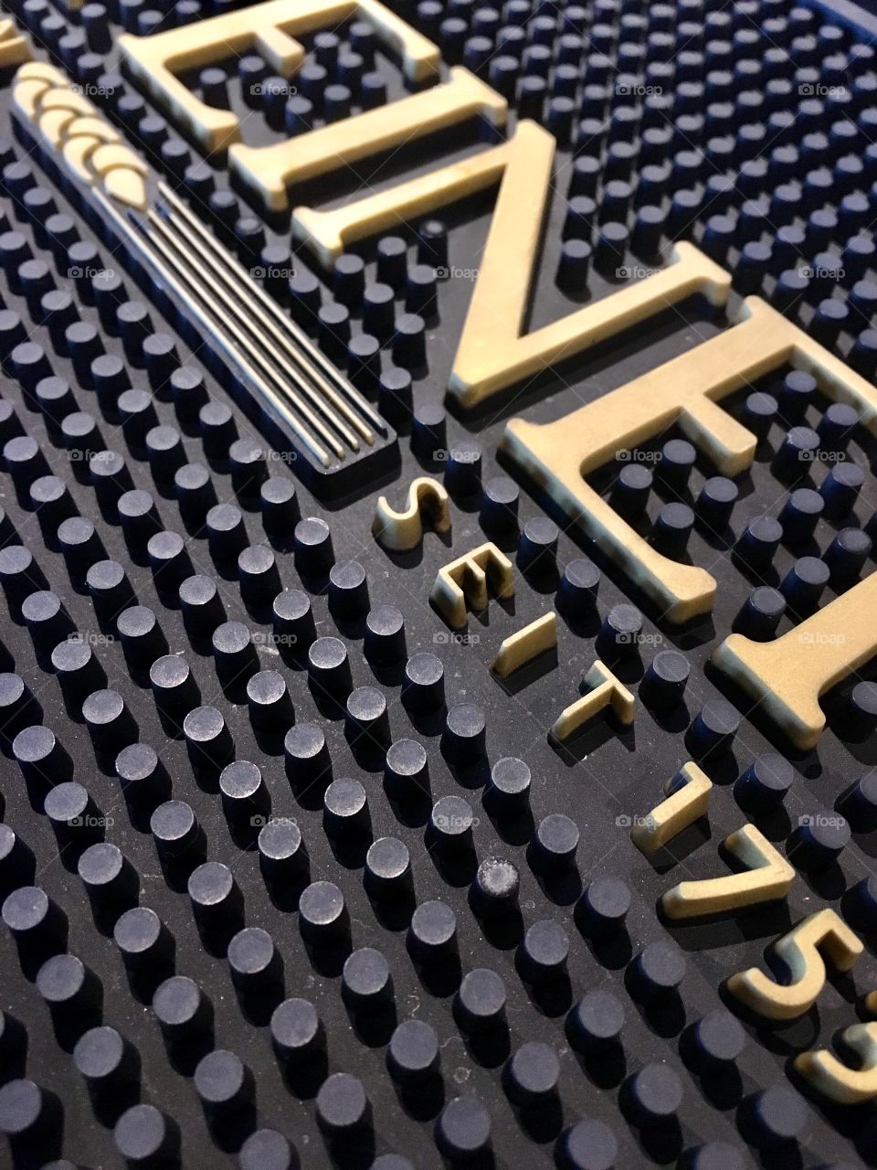 Rubber beer mat, at the bar. Gold writing, texture, weird angle.