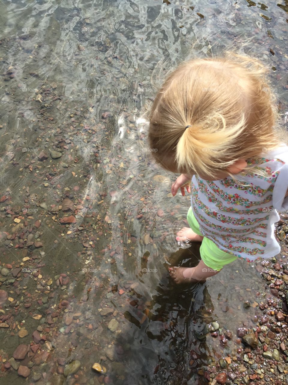 Two-year-old entranced in the cold water numbing her feet.
