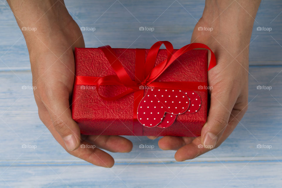 man's hand holding red gift box.  Christmas celebration