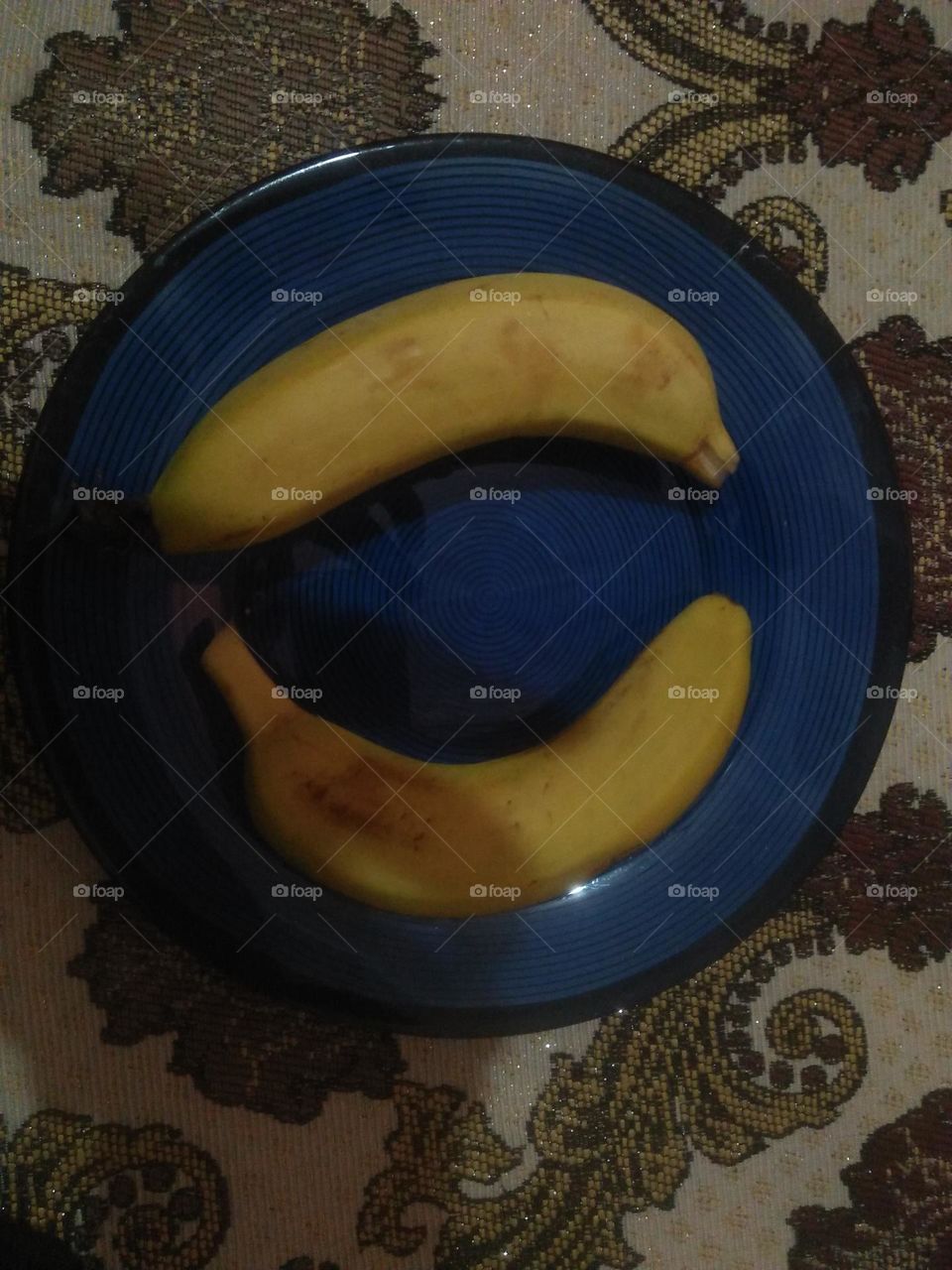 Two yellow bananas in the plate.