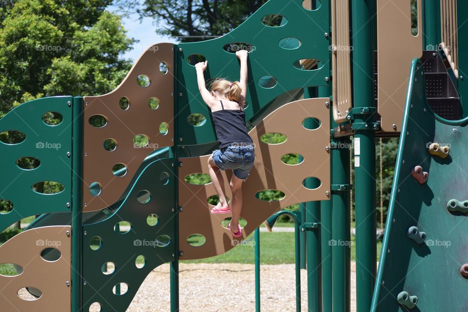 A little girl climbing on playground equipment