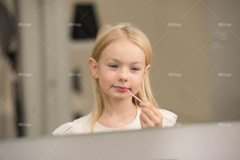 Young girl of Six taking on some lipgloss before a familyportrait photoshoot in Sweden.