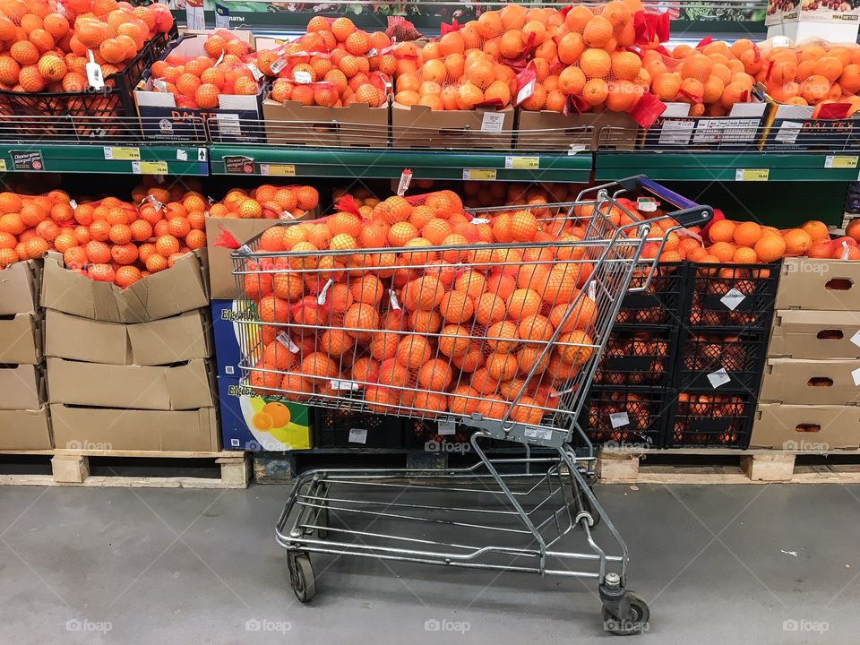 Supermarket cart and shelf full of oranges 