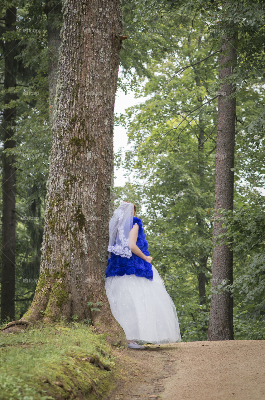Bride leaning at a tall tree