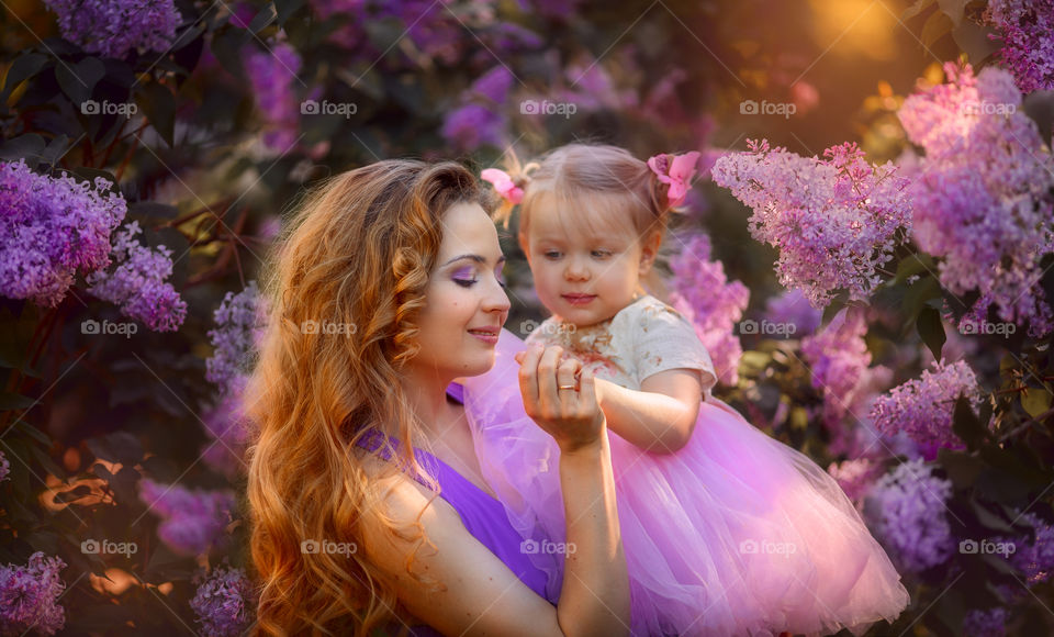 Beautiful young mother and little daughter in a lilac