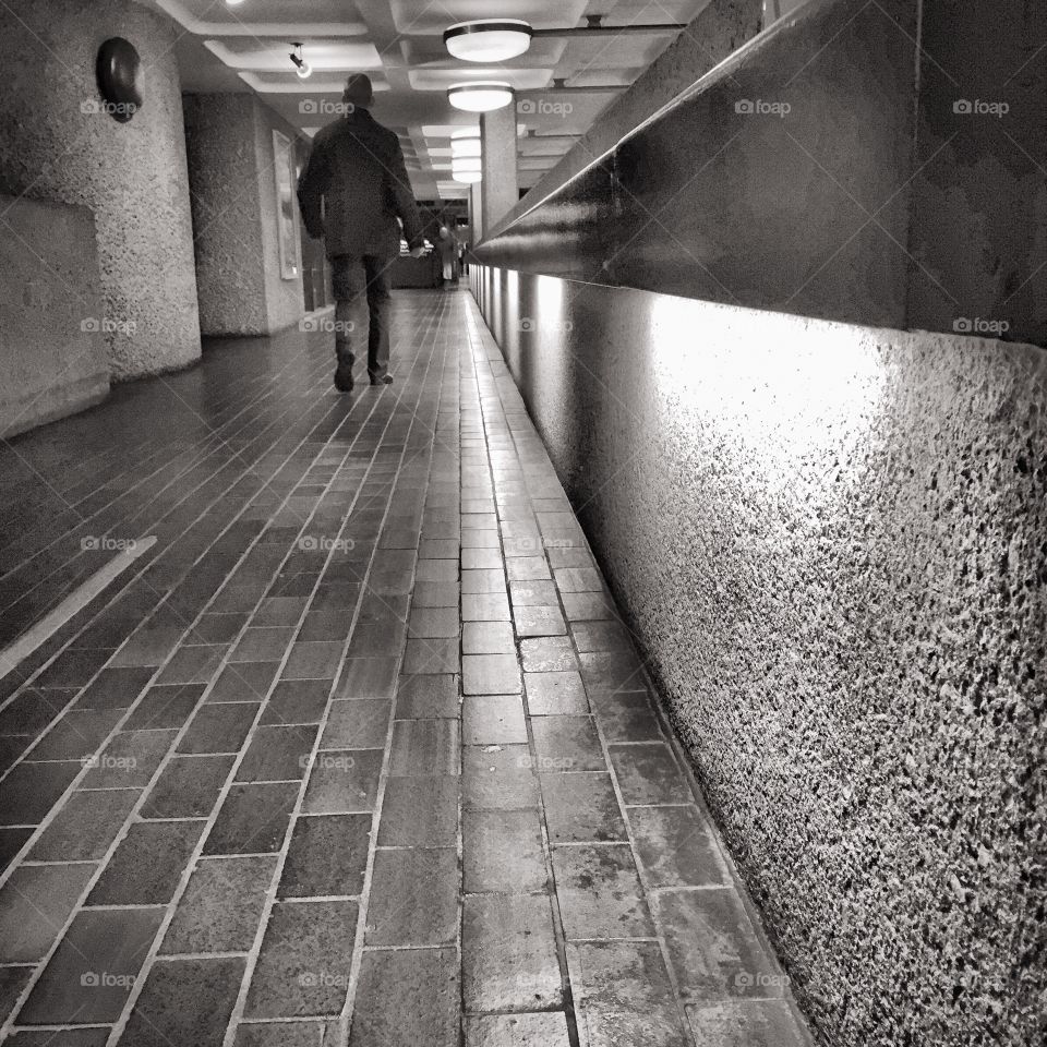 Man walking along pathway in black and white