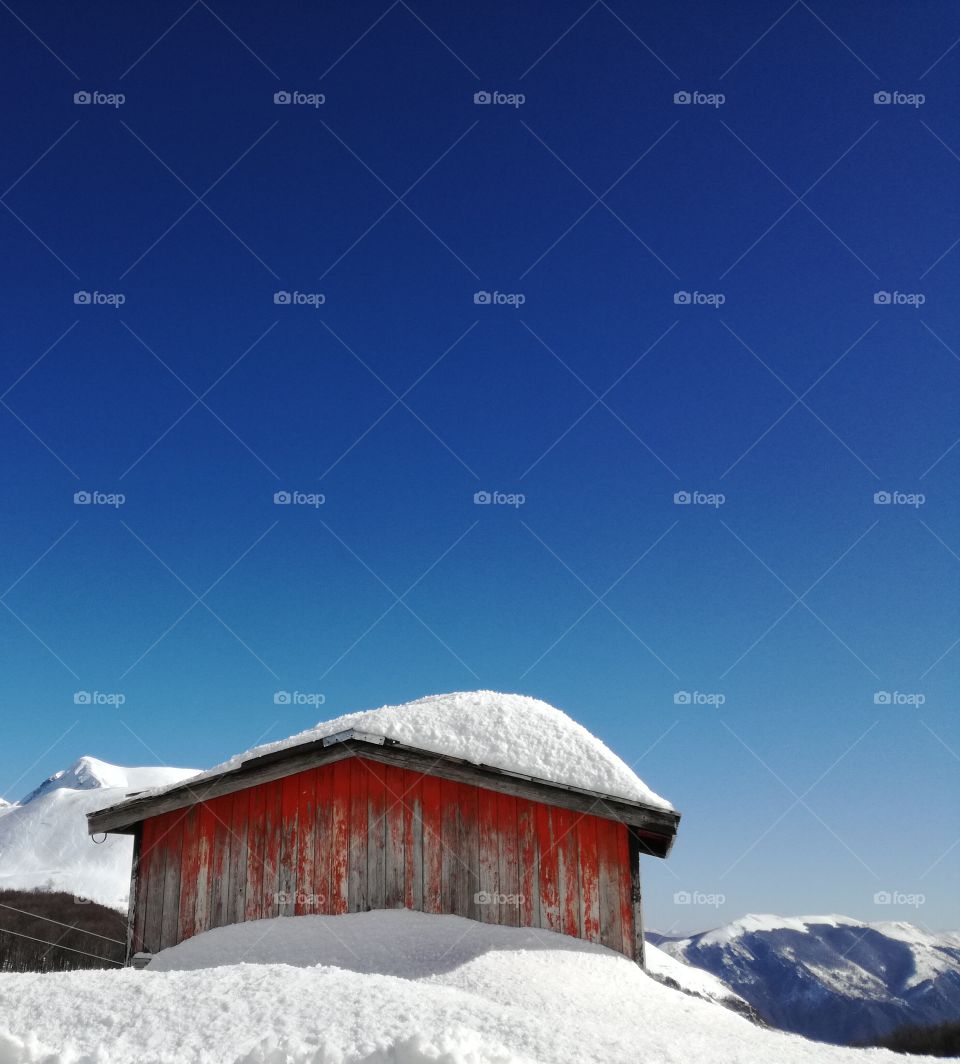 An old and small red house under the snow