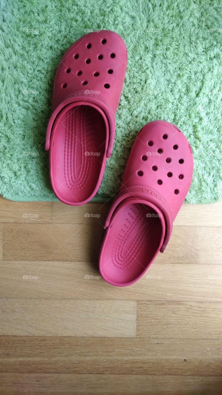 red Crocs slippers on green carpet
