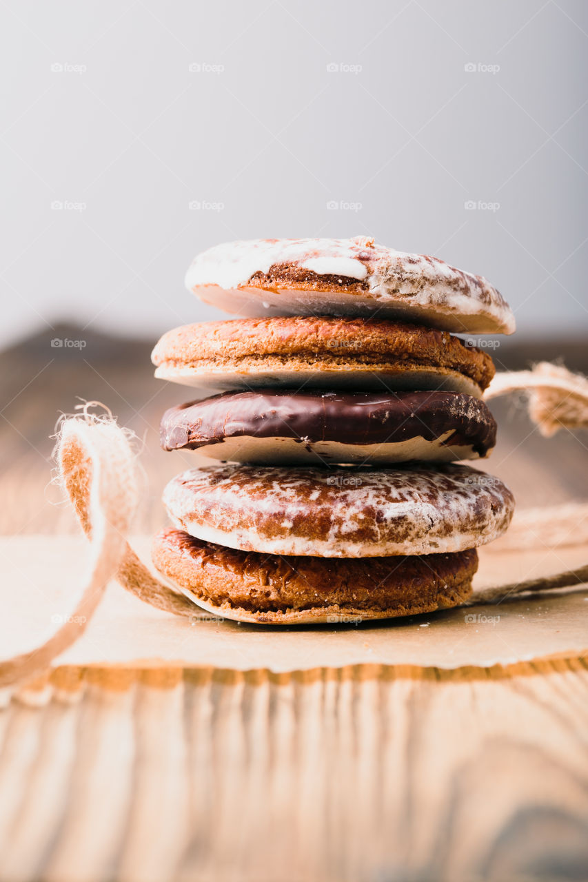 A few gingerbread cookies wrapped in ribbon on wooden table. Plain background. Portrait orientation