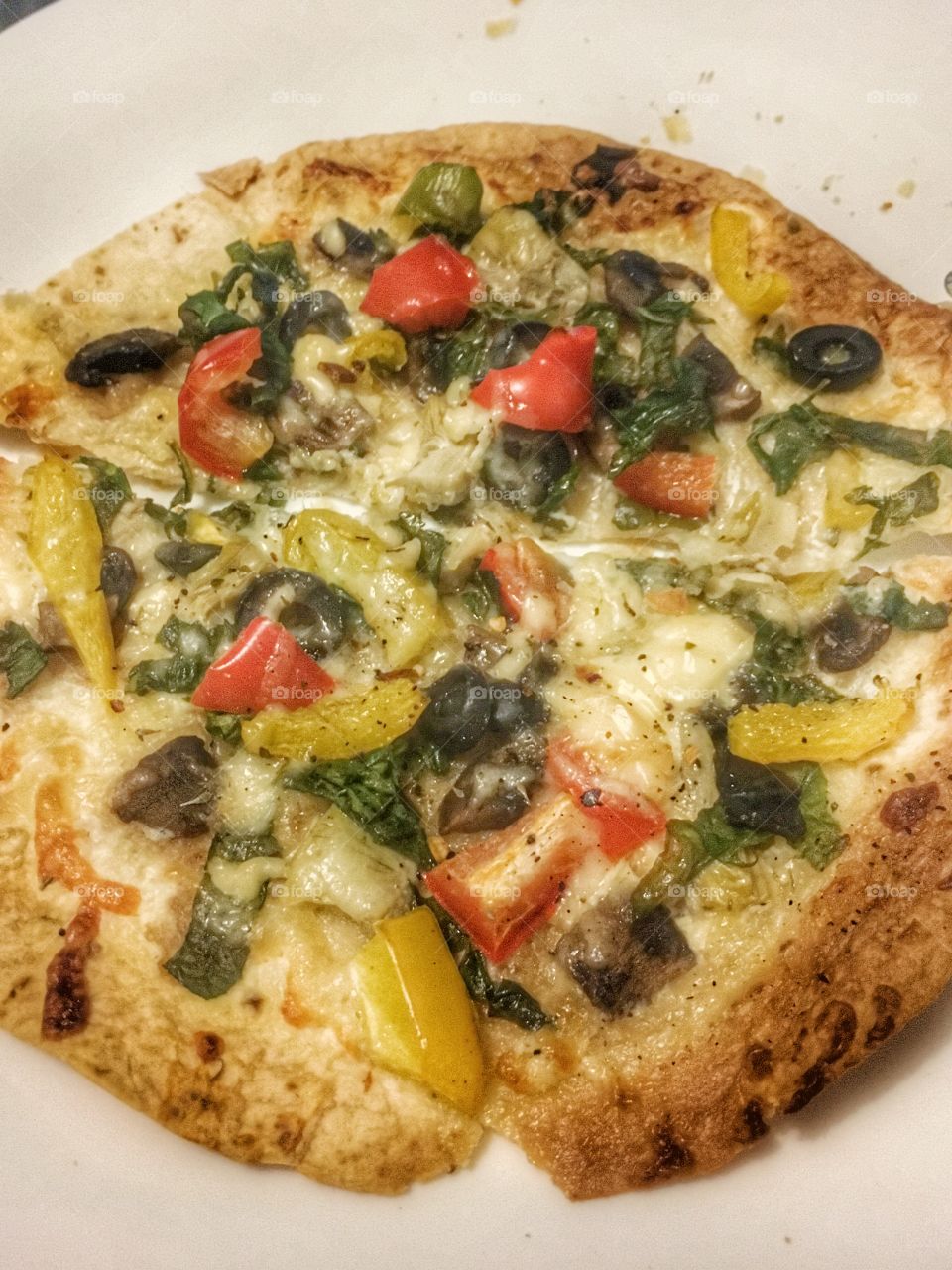 A healthy homemade garden pizza: olives, fresh mushrooms, spinach, red and yellow bell peppers, artichokes, cream and mozzarella cheese topped with herbs and spices. Pizzaaaa