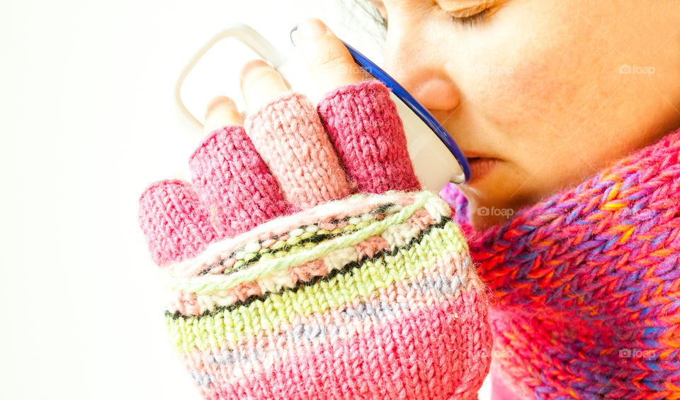 Woman wearing knitted gloves drinking tea