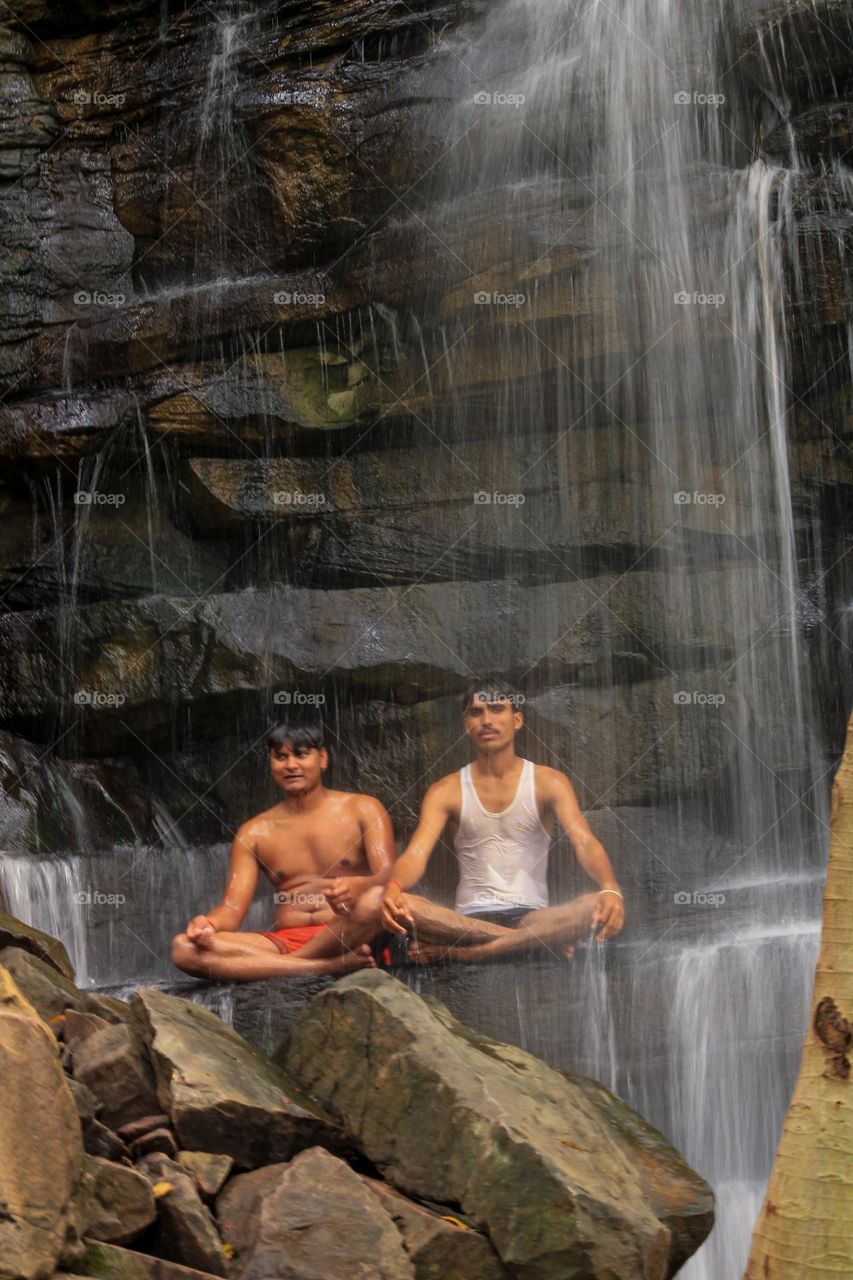 Indian boys sitting under a waterfall