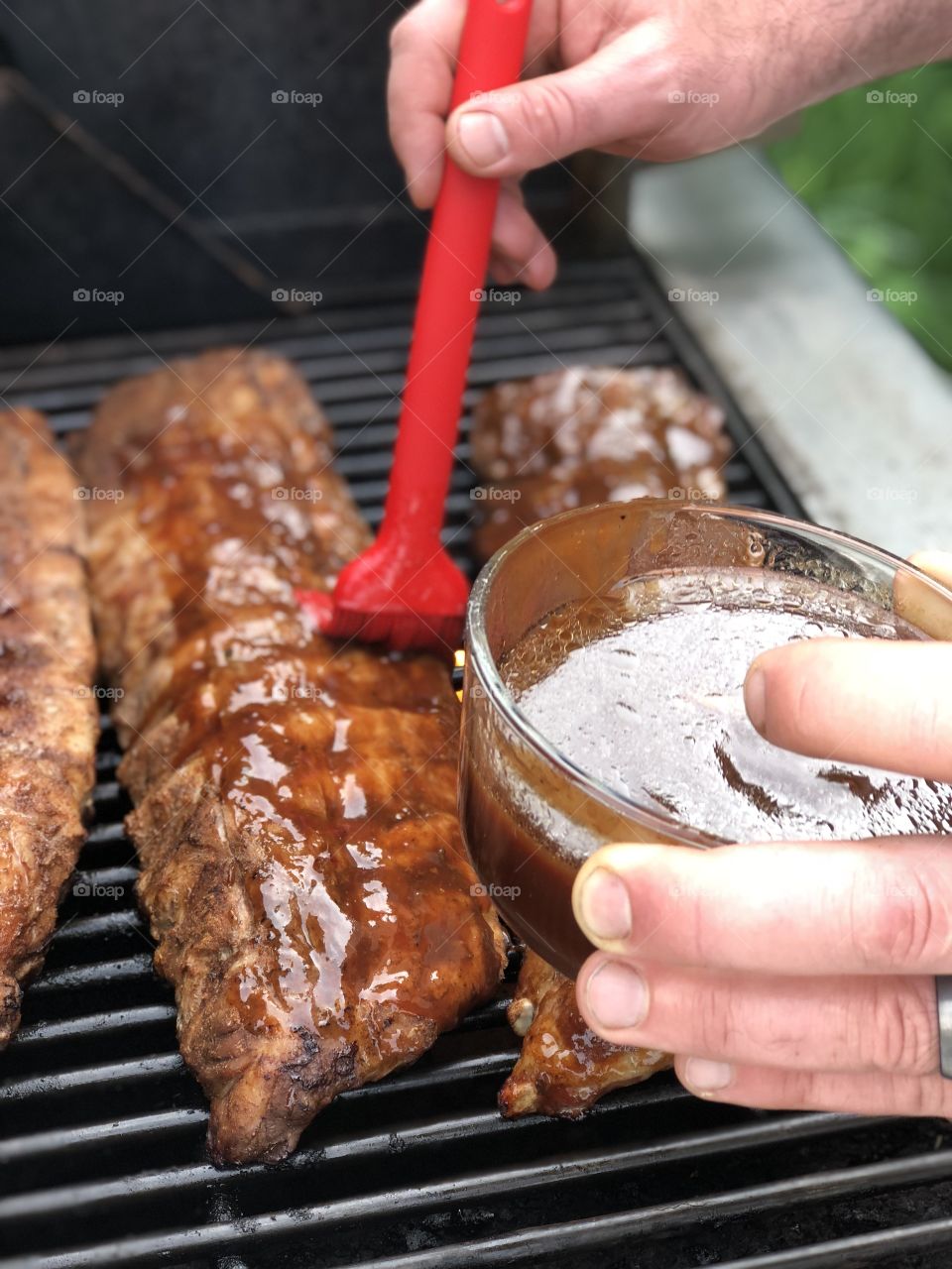 Ribs being brushed with barbecue sauce. Backyard Barbecue.