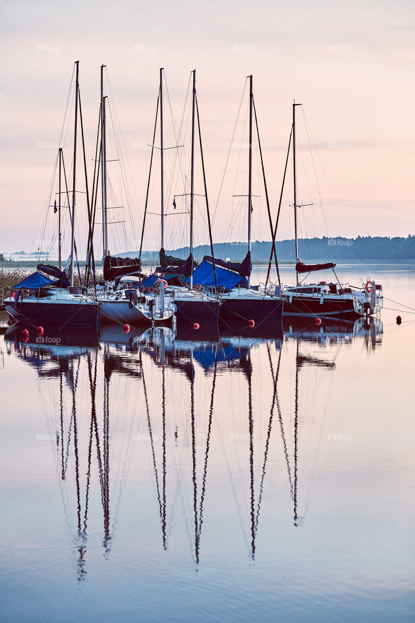 Yachts and boats moored in a harbour at sunrise. Candid people, real moments, authentic situations