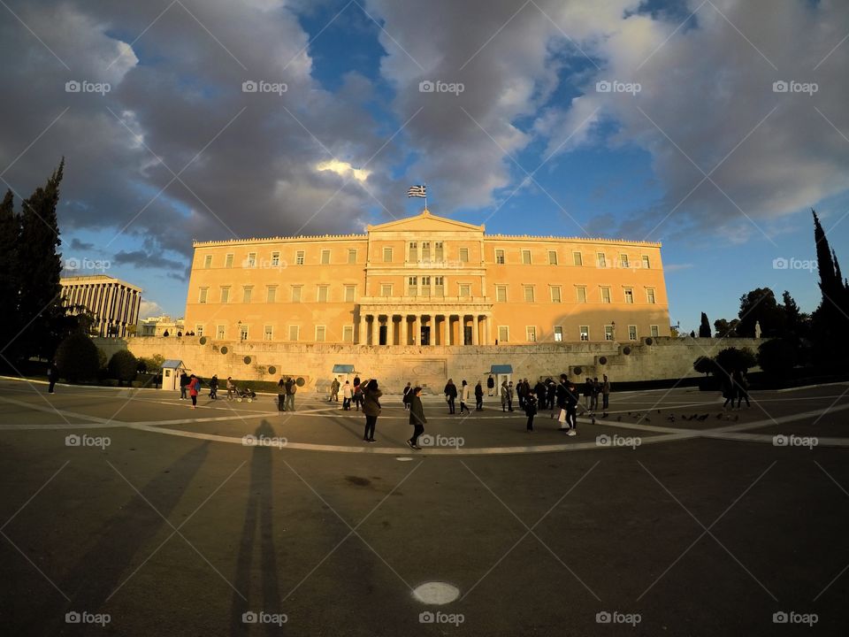 An architecture in Athens, Greece, with the Greece flag right above. This photo was taken during dusk.