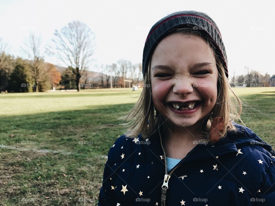 Adorable little girl with missing teeth wearing a beanie with the biggest smile on her face. 