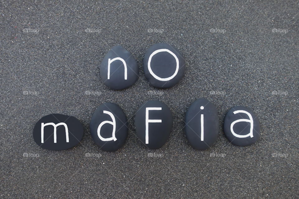 No mafia, slogan text composed with black colored stones over black volcanic sand