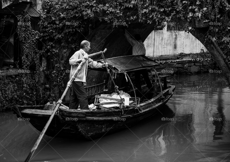 town canal ferry man small boat raining day ship black and white