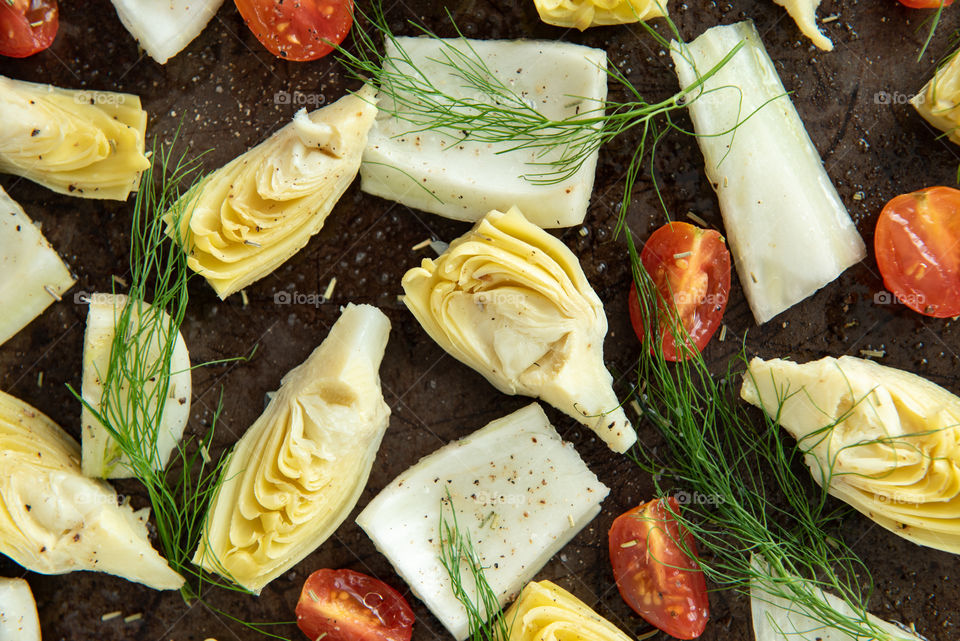 Closeup of artichoke, fennel and tomato on a sheet pan 