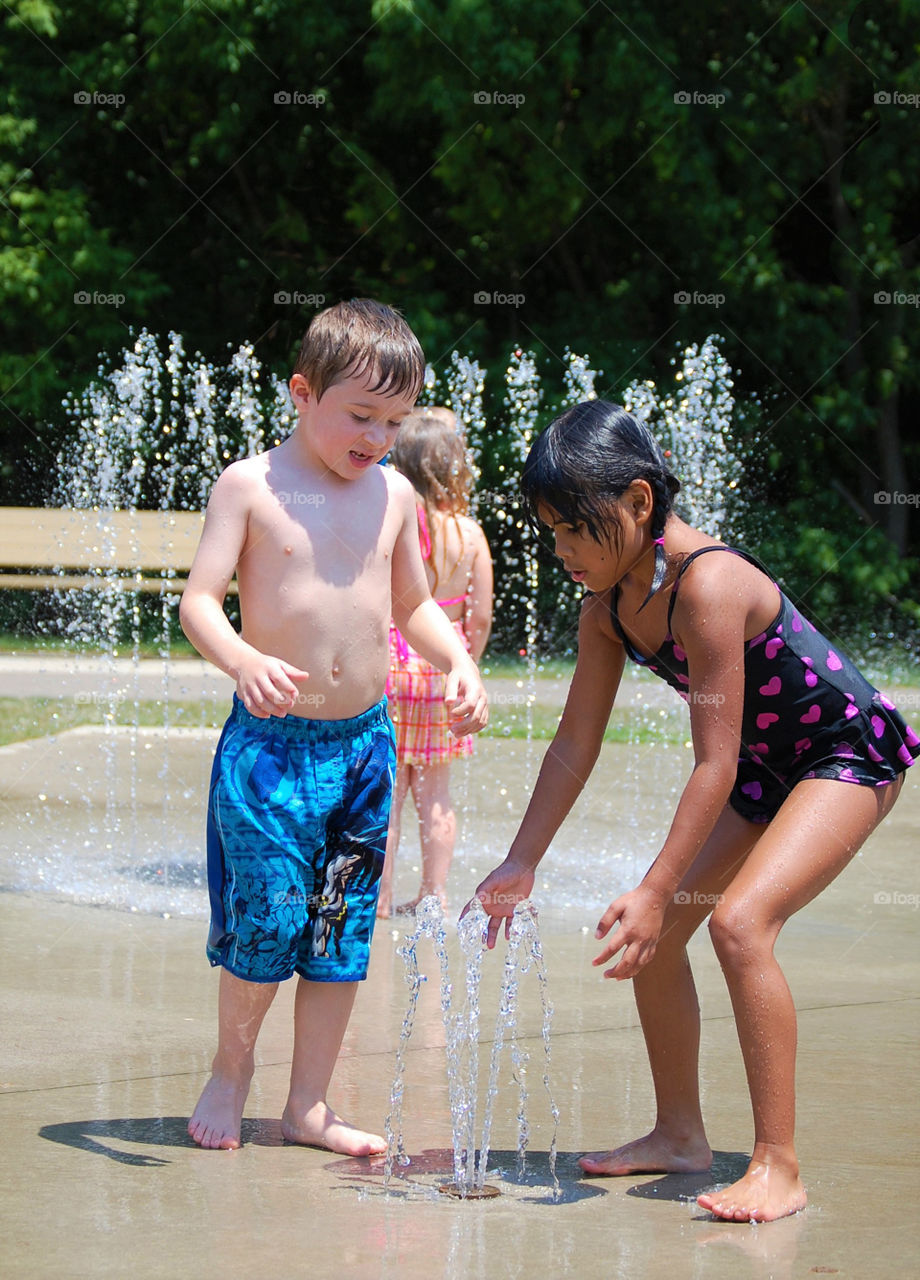 A boy and girl having fun on a splash pad