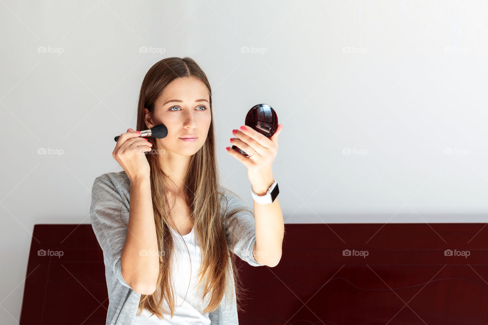 Beautiful young woman applying make up 