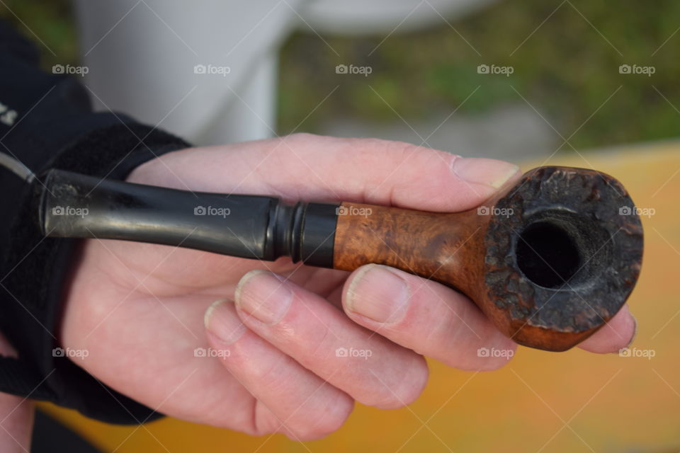 An elderly man holding a pipe