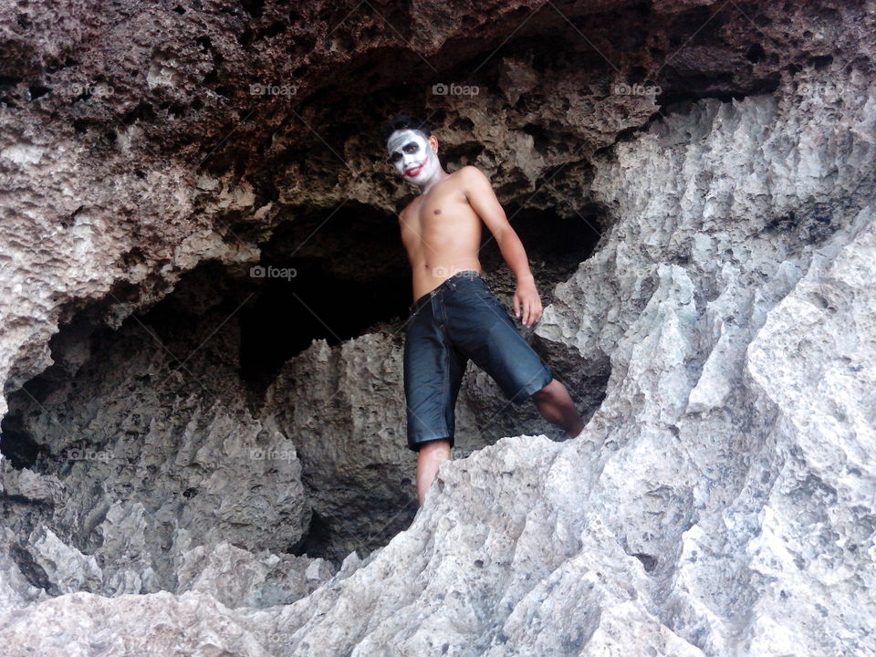 Man with face paint standing on rock in cave
