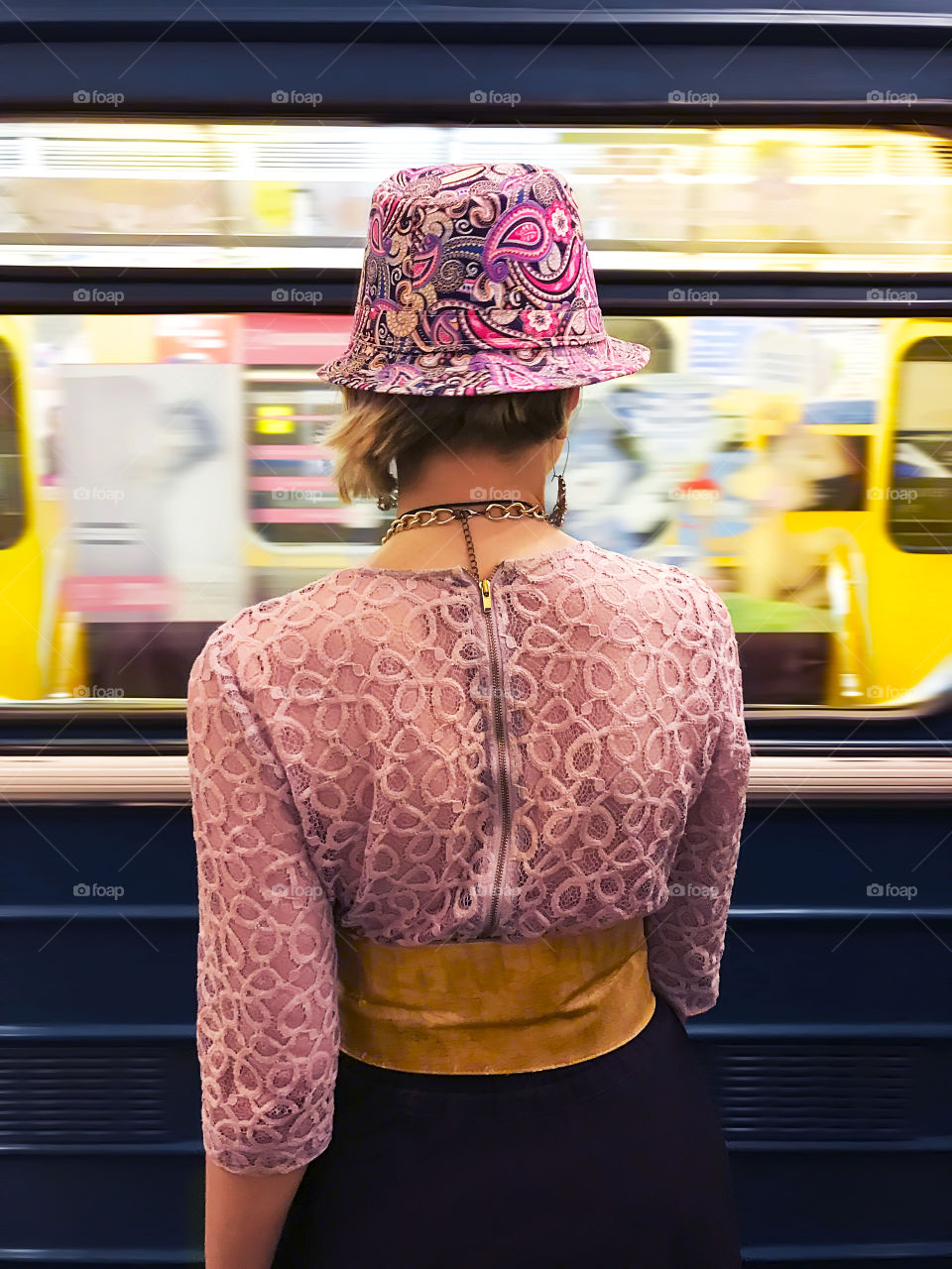 Fashionable woman wearing stylish colorful clothes and accessories waiting for a moving train to stop 