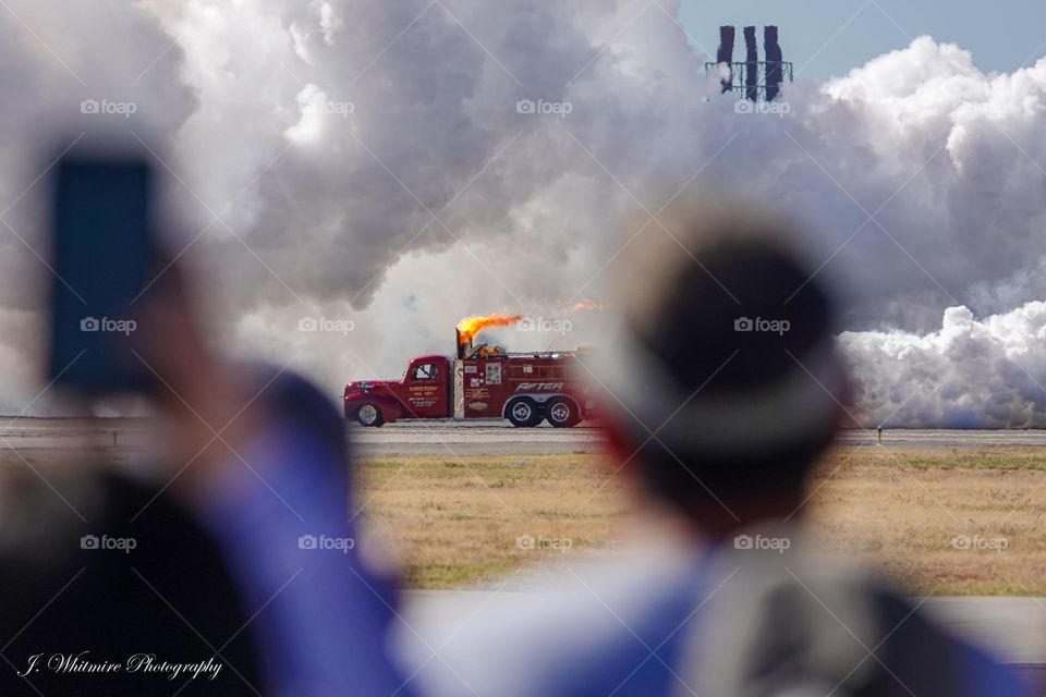 Spectators watch as a jet powered truck races down a runway at 300 miles per hour at a airshow