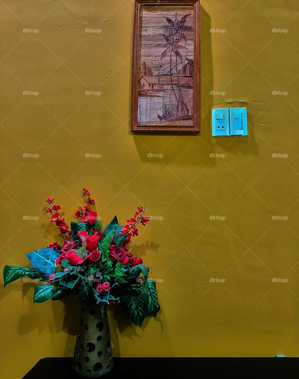 Interior room in yellow wall with single plant and single picture frame. Light background with copy space.