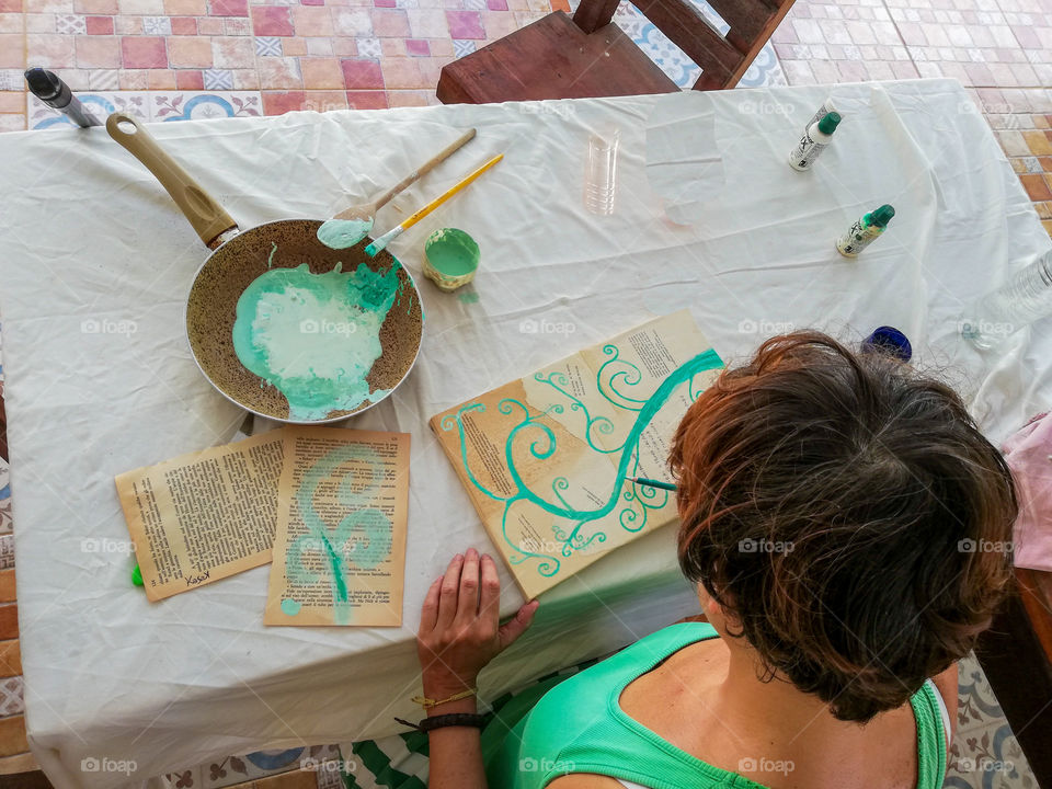 Woman painting with green colours on white table 