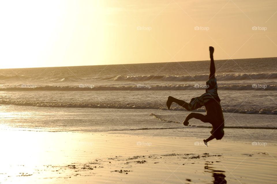 Man playing capoeira at sunset light 