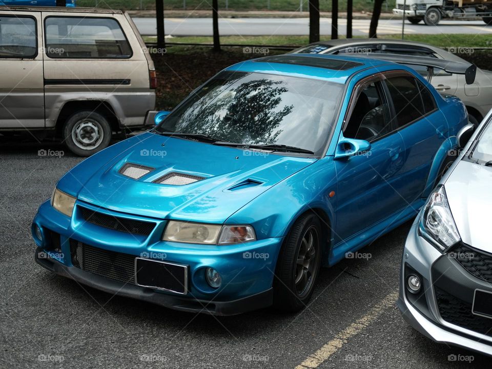 A blue car parked on a street in Kuala Lumpur, Malaysia