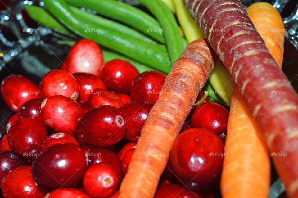 Colorful Cranberries in bowl for making traditional  Thanksgiving or Christmas cranberry sauce and trimmings of healthy organic carrots and green beans 