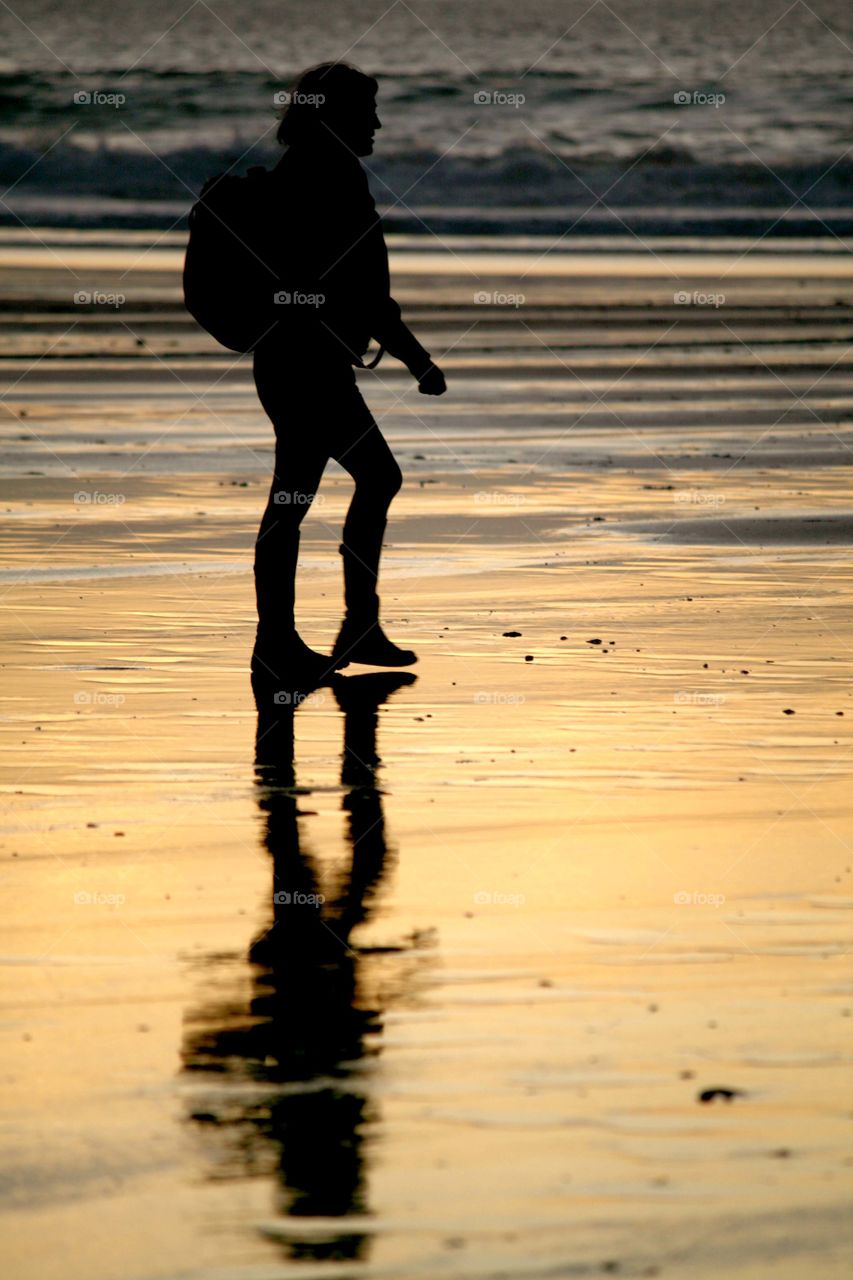 Walking in the sunset . Taking a stroll along Fistral Beach in Cornwall in the beautiful sunset reflecting on the wet sand 