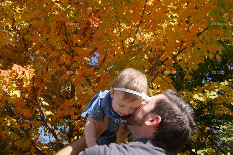 Father holding the daughter in front autumn trees