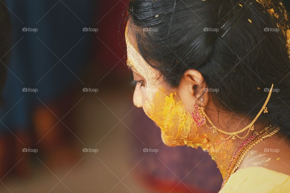Elders wearing bangles and applying turmeric which are blessings to the bride on the day before wedding for her happy marriage, which is an unique culture in Indian weddings