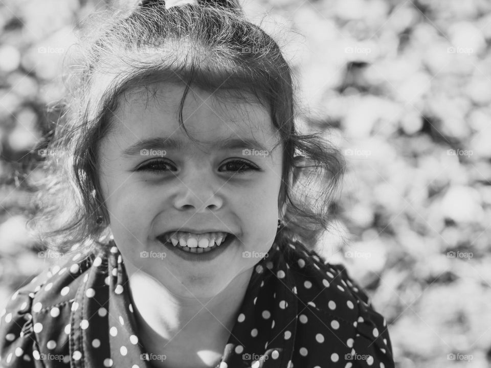 Portrait of one beautiful caucasian brunette girl with a happy smile on her face, close-up side view. Concept kids emotions, happy childhood.