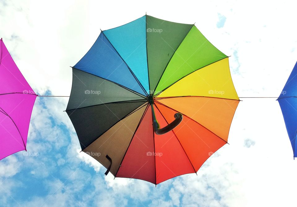 colorful rainbow color umbrella on the cloudy sky background